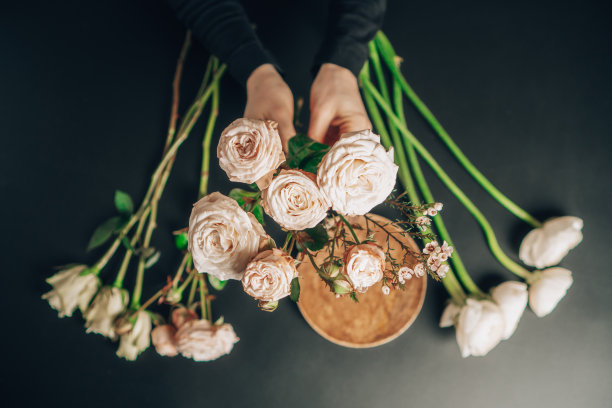 花商在他的桌子上方举着一朵牡丹玫瑰。花艺和花卉设计。图片下载