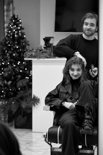 美丽的年轻女子在现代发廊。理发师检查发型图片下载