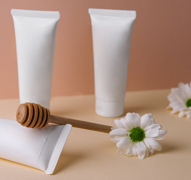 蜂蜜奶油与雏菊。白色瓶子化妆品。图片下载