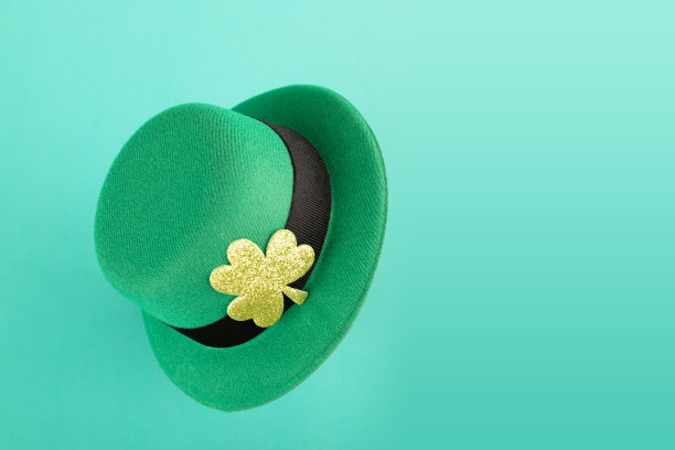 绿色爱尔兰妖精帽子与金色三叶草的绿色背景，圣帕特里克节，爱尔兰节日卡片图片下载