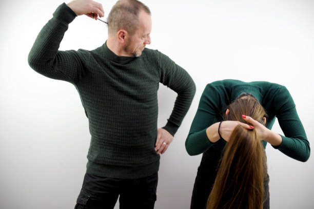 男人做鬼脸，一个女人靠过来，做了一个高马尾的发型，一个男人抱着自己的细辫子，并在白色背景上看着她玩微笑漫画笑戏弄图片下载