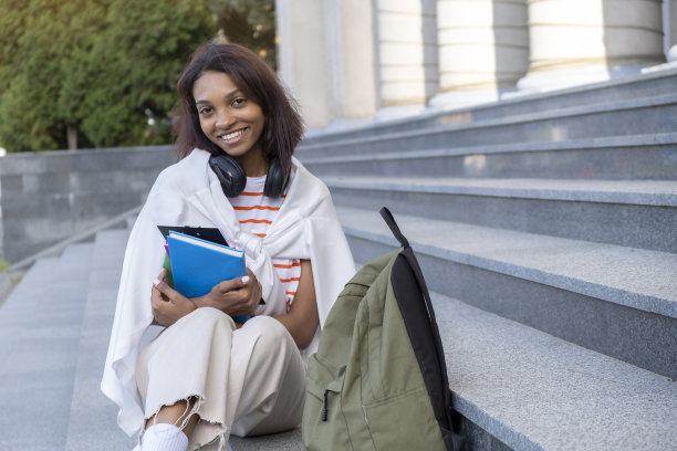 专注的年轻非洲学生坐在楼梯上使用图片下载
