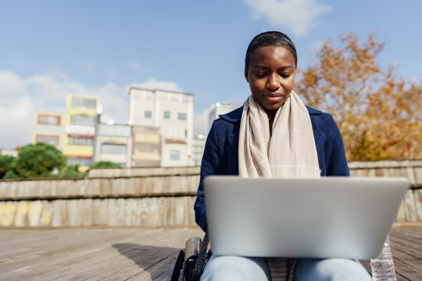年轻的非洲女商人坐在城市的长椅上使用笔记本电脑图片下载