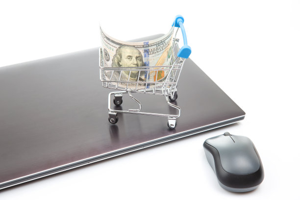 笔记本电脑背景上的美元购物车模型。网上商务销售。金融事业成功。图片下载