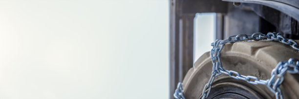 在雪地中使用安全防滑链。装载机或拖拉机与链条车轮特写。冬季行车安全图片下载