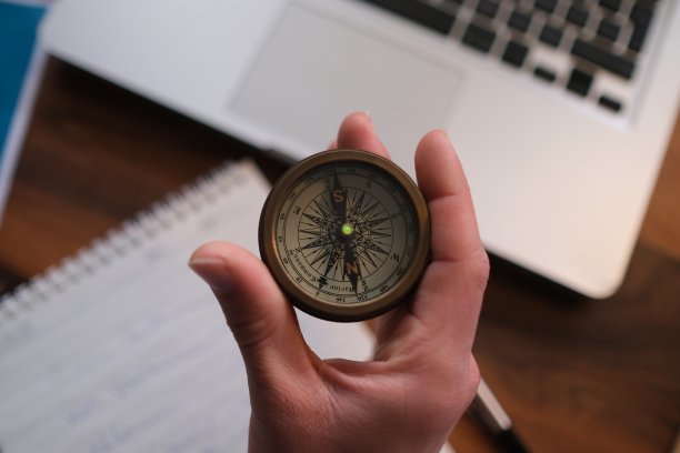 商人在笔记本电脑上拿着指南针，屏幕上显示客户网络连接图标，手机银行和全渠道图片下载