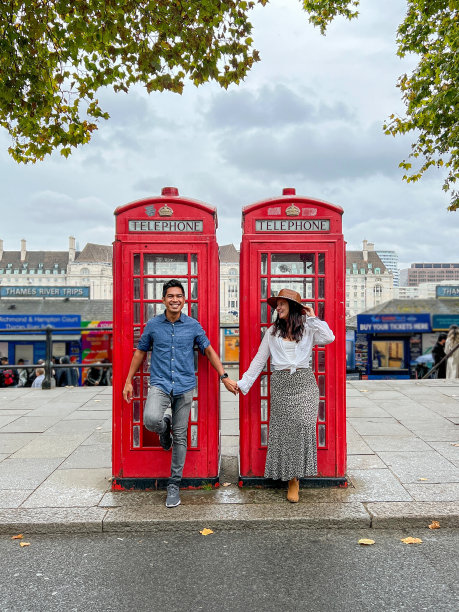 不同的情侣在红色电话亭附近摆姿势图片下载