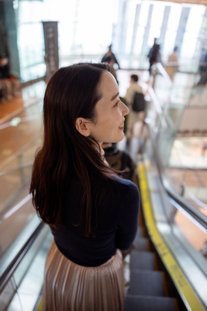 年轻的女商人正在扶梯上向下移动图片下载