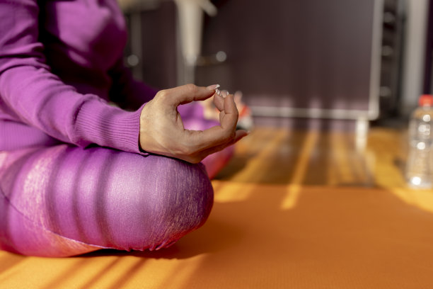 美丽的女人在家里练习瑜伽，坐在瑜伽垫上冥想，微笑放松。图片下载