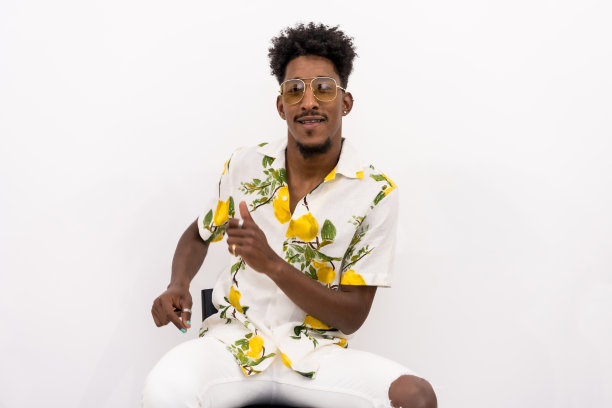 一名年轻的古巴男子穿着花衬衫，戴着太阳镜，在白色背景上微笑着跳舞图片下载