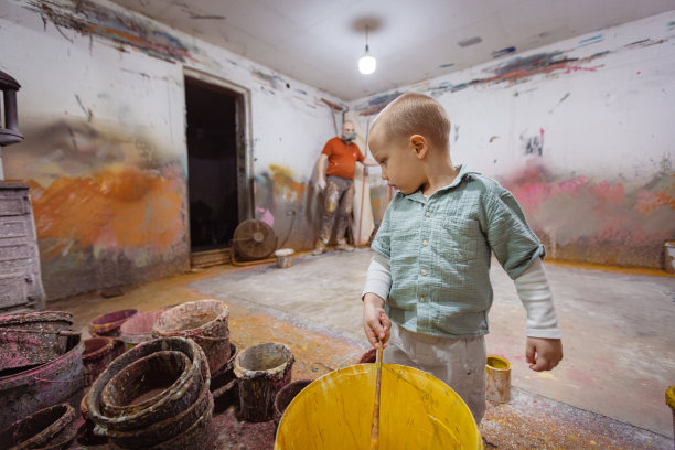 漂亮的金发小男孩拿着一桶黄色颜料图片下载