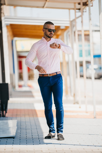 酷帅的白人男子穿着优雅的浅粉色衬衫和太阳镜在户外摆姿势图片下载