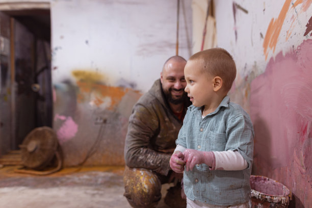 父亲和满手污渍的可爱幼儿男孩图片下载