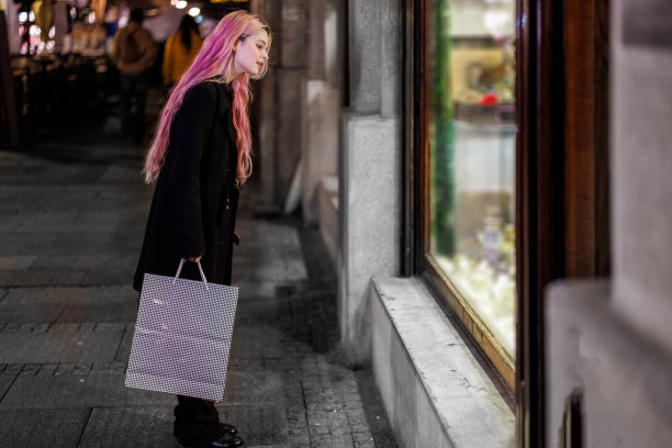 一位年轻女子晚上走在城区里，她喜欢购物。图片下载