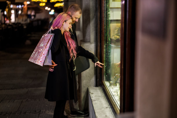 一对相爱的年轻情侣走在市区，晚上一起逛街。图片下载