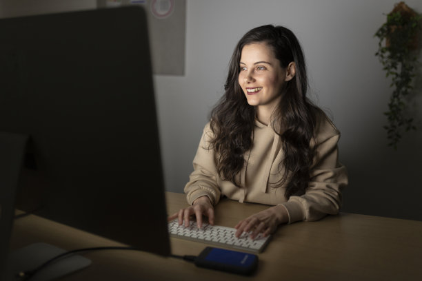 女性坐在家庭办公室的办公桌前，用笔记本电脑工作到深夜;在家远程加班的女性网页设计师图片下载