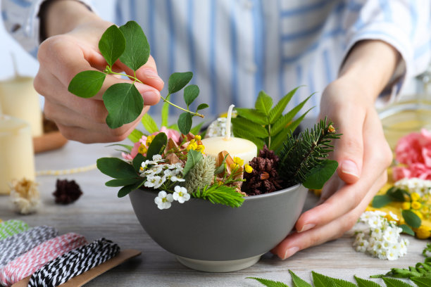 女子在木桌上用蜡烛制作花卉构图，特写。手工工艺大师班图片下载