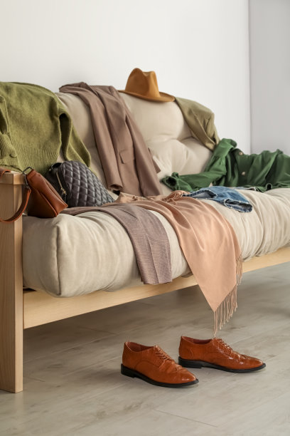 客厅沙发上凌乱的一堆衣服和配饰图片下载