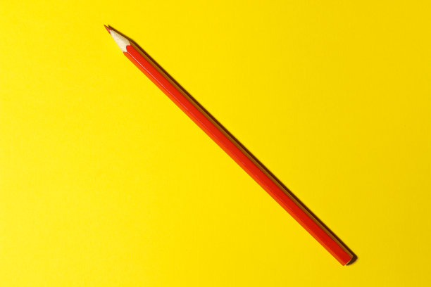 一支红色铅笔在明亮的黄色背景上。从上面看。文具。图片下载