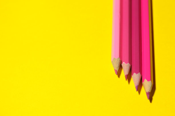 粉红色的铅笔在明亮的黄色背景上带有刺眼的阴影。文本空间图片下载
