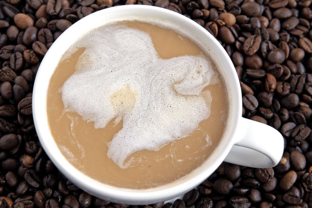 白色热咖啡，牛奶泡沫在烘焙咖啡豆的背景。一杯热拿铁和茶托。美味时尚的卡布奇诺。特写镜头。咖啡店。咖啡产品广告的概念。图片下载