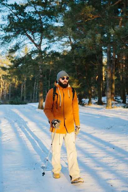 一个男人背着背包在冰雪覆盖的冬季森林里徒步旅行。图片下载