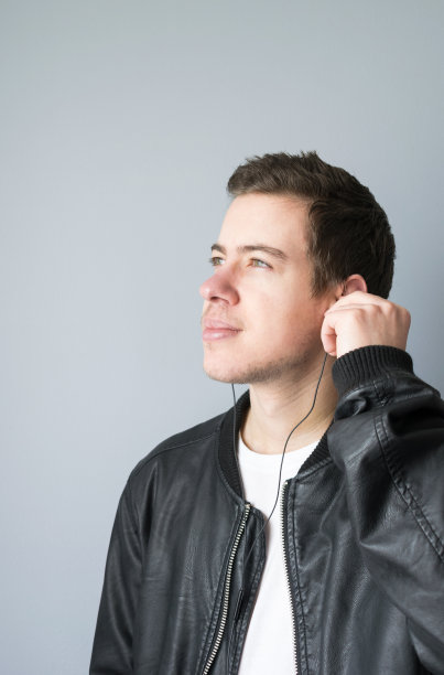 带着皮夹克和耳机的青少年的侧面视图图片下载