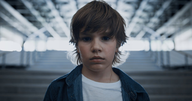 一个十几岁的男孩独自站在学校的楼梯上。男生觉得难过不开心图片下载