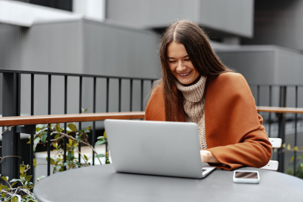 年轻女子工作与她的笔记本电脑坐在桌子在街上图片下载