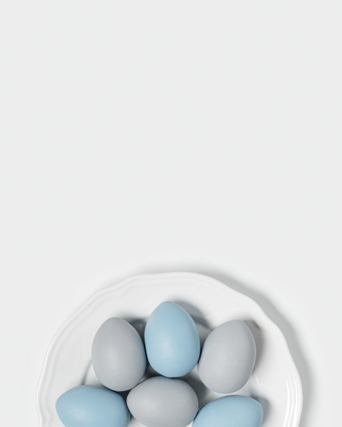 把彩蛋用粉彩染成蓝色、灰色，放在白色的圆盘上。快乐复活节节日概念，庆祝食物，装饰鸡蛋，中性时尚彩色卡片。俯视图图片下载