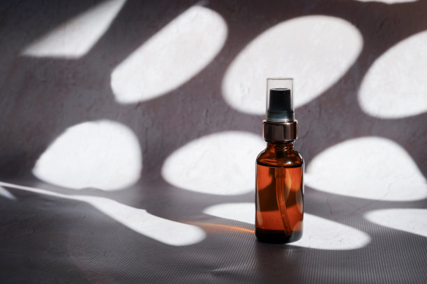 化妆品油在玻璃瓶瓶子上的混凝土背景与反射和对比的阴影图片下载