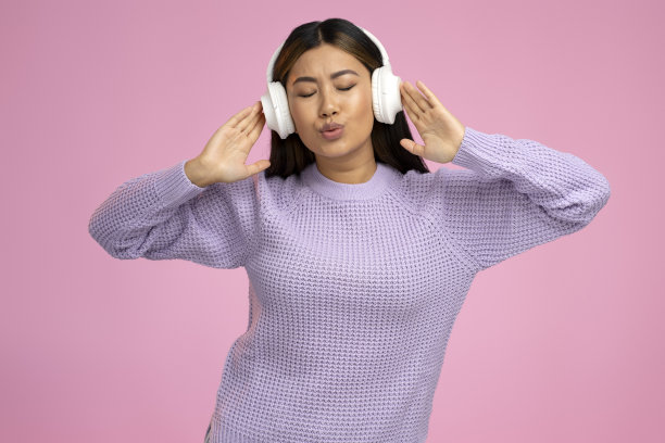 青少年戴着耳机，在粉红色的背景下享受着最喜欢的音乐图片下载