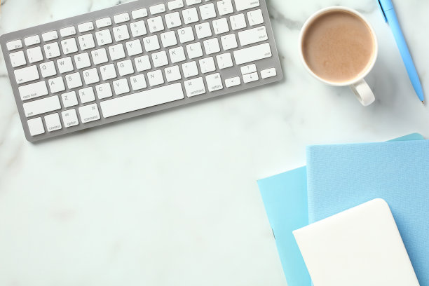 办公桌桌上有键盘，咖啡杯，蓝色纸笔记本。平铺，俯视图。图片下载