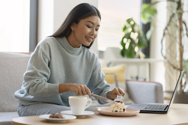 可爱的亚洲女孩吃美味的甜点，同时在舒适的咖啡馆工作图片下载