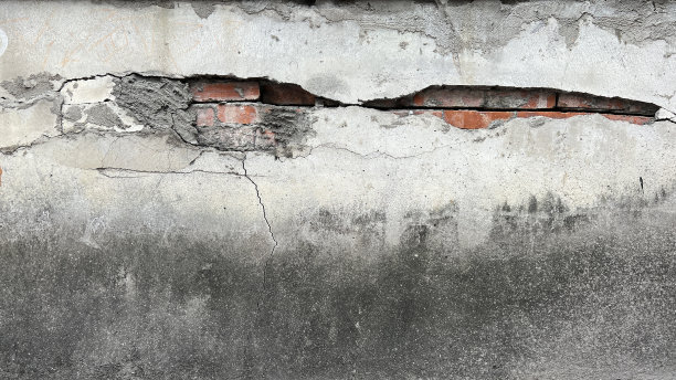 灰白色的水泥墙已经破损，裂缝露出了红砖墙图片下载