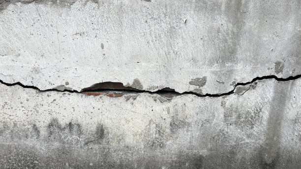 灰白色的水泥墙已经破损，裂缝露出了红砖墙图片下载