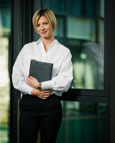 垂直拍摄的短发金发女商人文件夹在办公室图片下载
