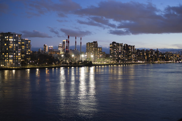 罗斯福岛在夜间灯火通明，身后是皇后区的发电厂和遥远的长岛市。从曼哈顿上东区横跨东河的全景。图片下载