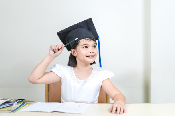 一个开朗的亚洲小女孩的肖像，戴着一顶白色背景上孤立的学士帽图片下载