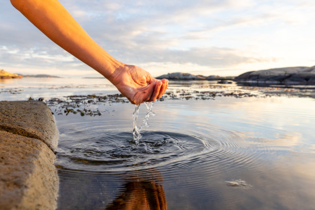 日落时分，双手从海里舀水图片下载