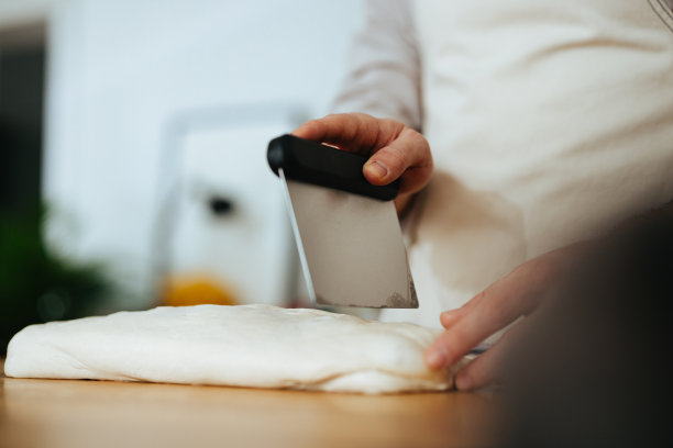 特写镜头是一个不知名的男人在厨房里切面团图片下载