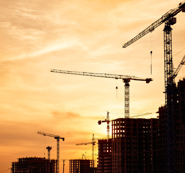 塔吊和新建筑的轮廓在建筑工地在黄色的天空日落图片下载
