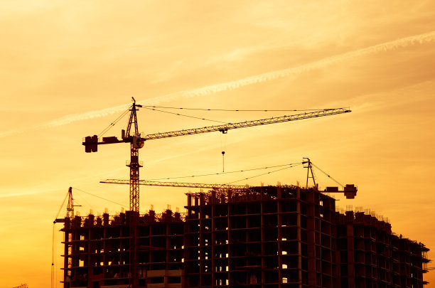 塔吊和新建筑的轮廓在建筑工地在黄色的天空日落图片下载
