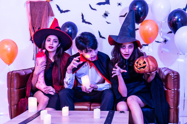 快乐的朋友们穿着万圣节服装和化妆，在派对上用南瓜摆姿势庆祝万圣节图片下载