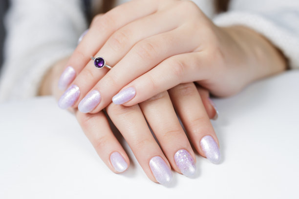 一个年轻女人的手。指甲上涂有珍珠凝胶和亮片图片下载