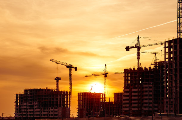 塔吊和新建筑的轮廓在建筑工地在黄色的天空日落图片下载