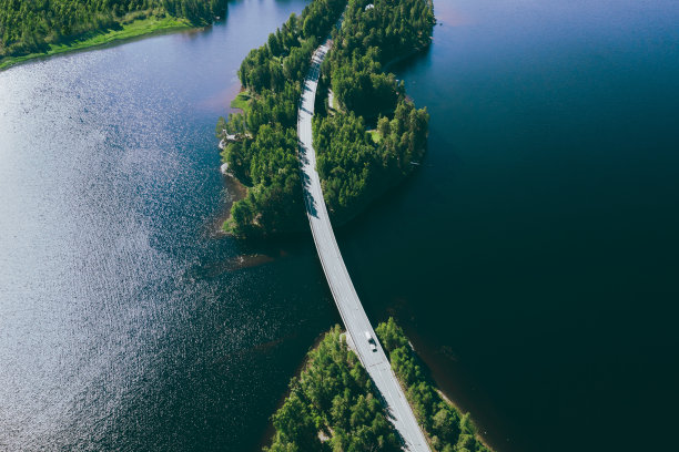 在芬兰，蓝色湖水和绿色森林上的道路鸟瞰图。图片下载