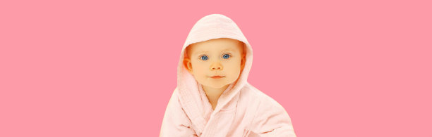 可爱的小婴儿肖像在柔软的浴袍上粉红色的背景图片下载