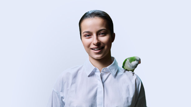 年轻的十几岁女性和绿色宠物鹦鹉，白色背景图片下载