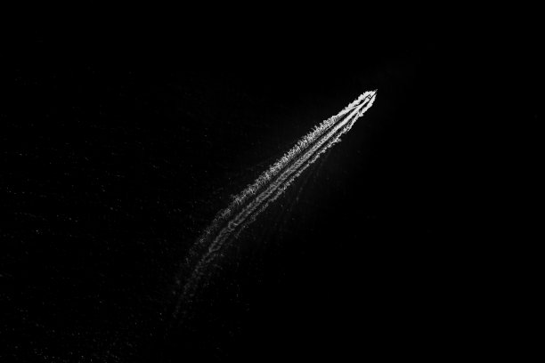 黑色背景鸟瞰图上，黑白相间的游客小快艇全速航行，在大海中溅起水花图片下载